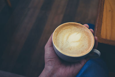 Cropped hand holding coffee on table