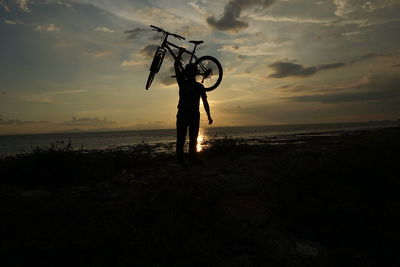 Silhouette person standing on beach against sky during sunset