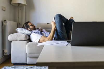 Man writing notes on couch in cozy living room