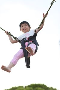 Low angle view of boy jumping against sky