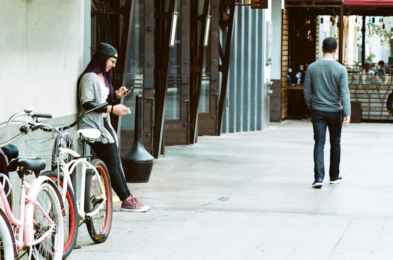 full length, lifestyles, bicycle, casual clothing, rear view, men, standing, built structure, leisure activity, architecture, sidewalk, building exterior, street, walking, transportation, side view, low section, day