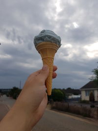 Midsection of person holding ice cream against sky