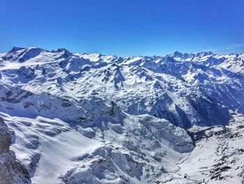 Scenic view of snowcapped mountains against blue sky