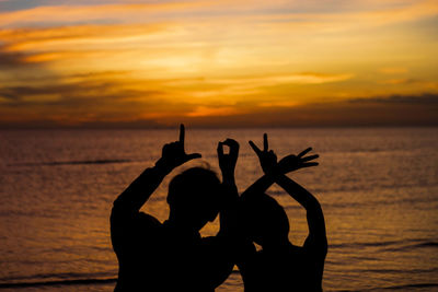 Silhouette people against sea during sunset