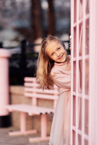 Portrait of smiling young woman standing by railing