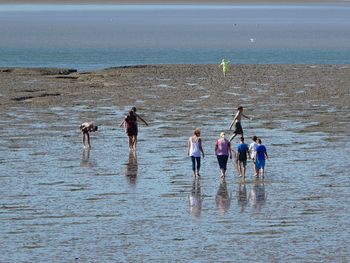 People standing on beach by sea against sky