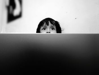 Portrait of boy hiding behind curtain at home