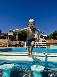 Full length of shirtless boy jumping in swimming pool