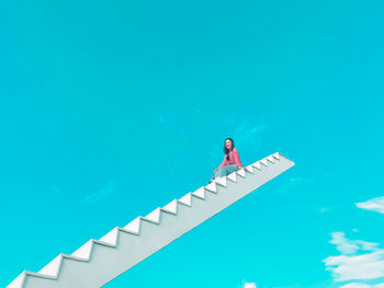 Low angle view of person standing on staircase against sky