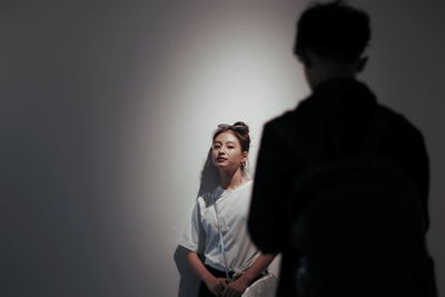 Young woman standing against wall