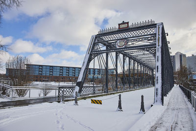 Bridge over snow covered landscape against sky