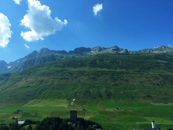 Scenic view of green landscape and mountains against sky