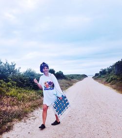 Full length of woman standing on road against sky