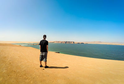 Full length of man standing on beach against sky