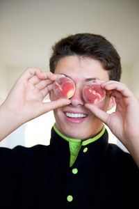 Boy holding peaches over eyes