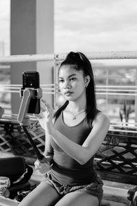 Portrait of woman sitting on railing