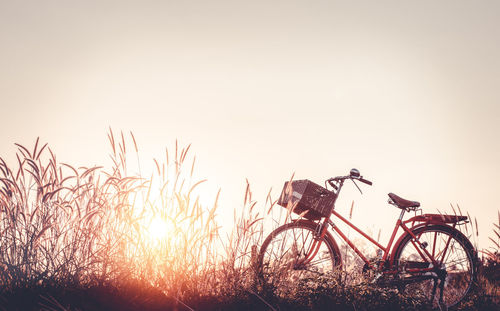 Bicycle on field against clear sky during sunset