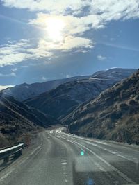 Road leading towards mountains against sky