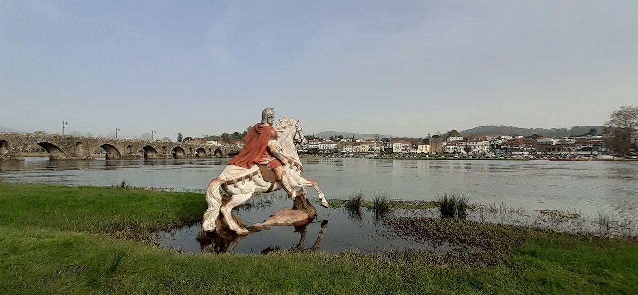 VIEW OF STATUE BY RIVER AGAINST SKY