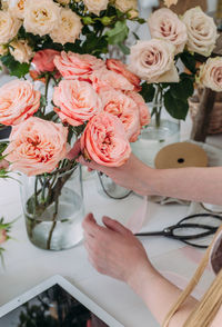 Cropped hands of woman holding rose in vase