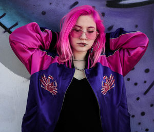 Portrait of beautiful young woman standing against wall