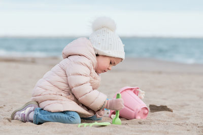 Little girl is digging in the sand on a cold day at the beach