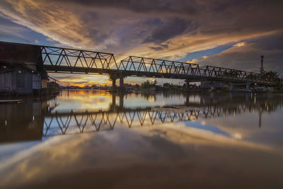 Bridge over river against sky during sunset