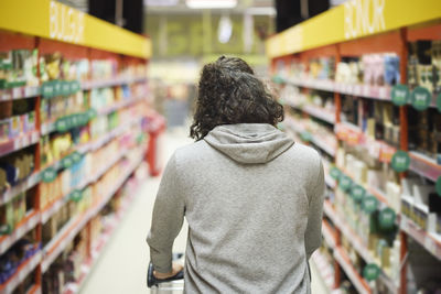 Rear view of man doing shopping in supermarket