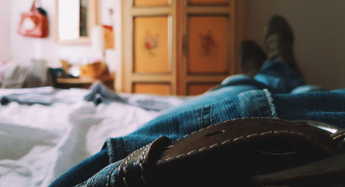 Low section of man lying on bed at home