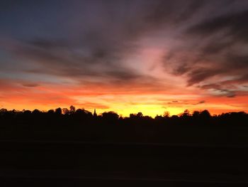 Silhouette landscape against dramatic sky during sunset