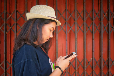 Portrait of a young woman looking away while standing on fence