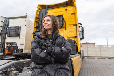 Happy mature woman standing against truck