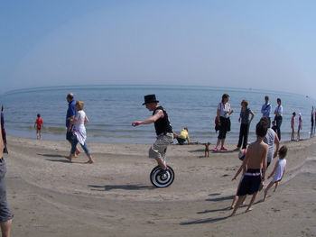 People on beach against clear sky