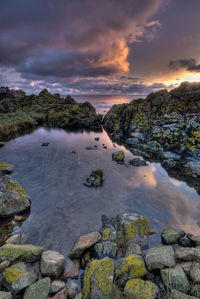 Scenic view of a rockpool against sky during sunrise.