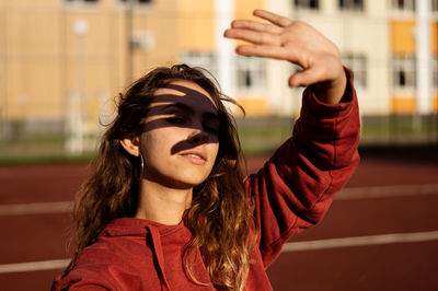 Portrait of young woman shielding eyes at running track
