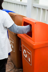 Closeup a hand throwing empty plastic bottle in recycling bin.