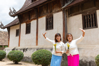 Happy friends standing against building