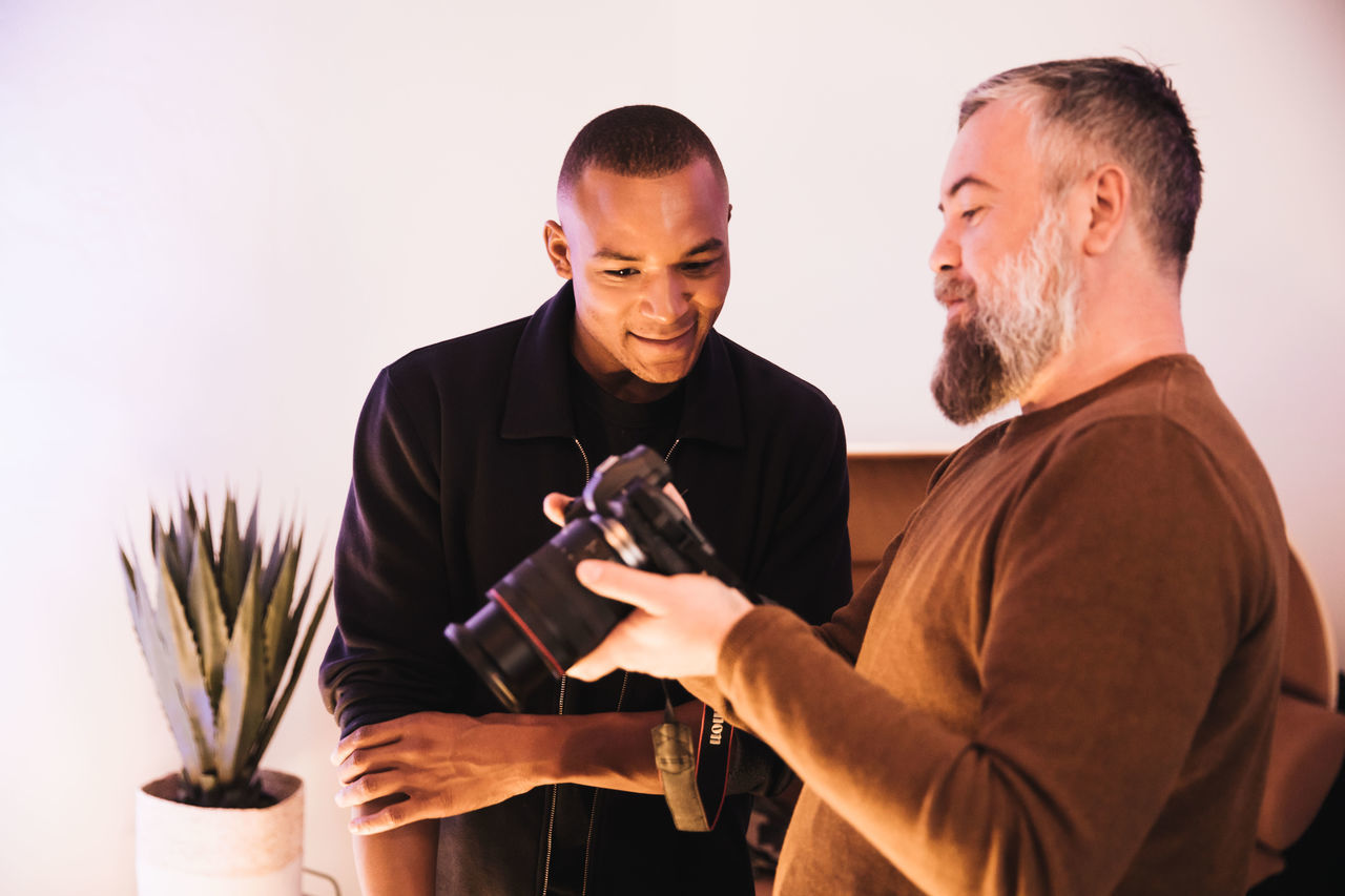 YOUNG MAN HOLDING CAMERA WHILE STANDING ON SOFA