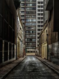 Empty road amidst buildings in city
