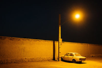 Car on illuminated street against clear sky at night