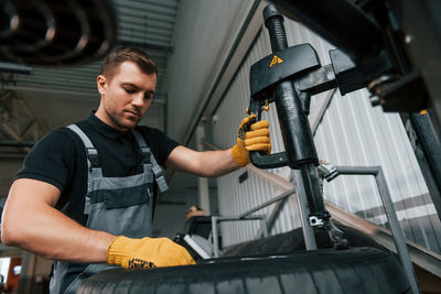 Strong hands. man in uniform is working in the auto service.