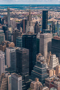 Aerial view of illuminated skyscraper buildings in city at day at high angle