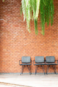 Empty chairs against brick wall