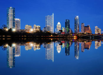 Reflection of buildings in water against blue sky