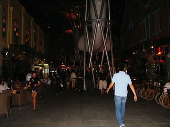 Rear view of man standing in illuminated city at night