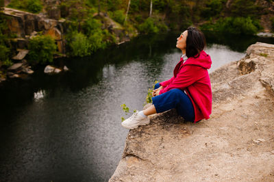Side view of young woman sitting on rock
