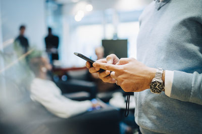 Midsection of man holding mobile phone