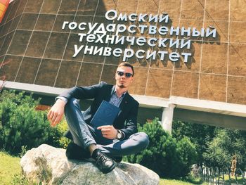 Full length of young man sitting on wall