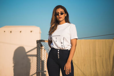 Portrait of young woman standing against sky