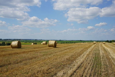 Hay bales on field against sky